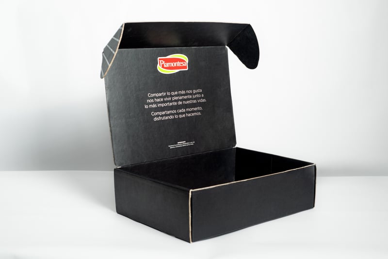 Caja mailer abierta negra de Piamontesa con mensaje interior.