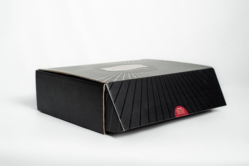 Caja mailer negra cerrada de Piamontesa con gráfica radial.