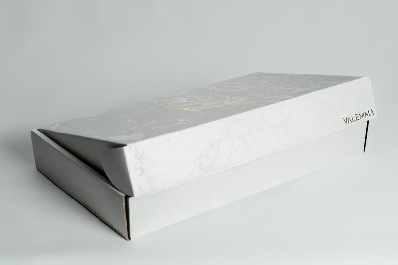 Detalle de caja premium VALEMMA con textura tipo mármol.