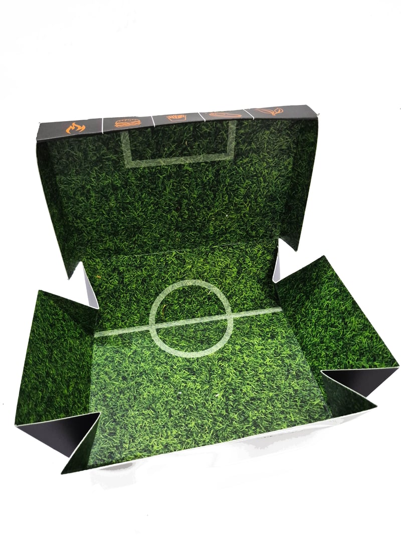 Caja para hamburguesa abierta mostrando interior con diseño de cancha de fútbol, de SellerPack