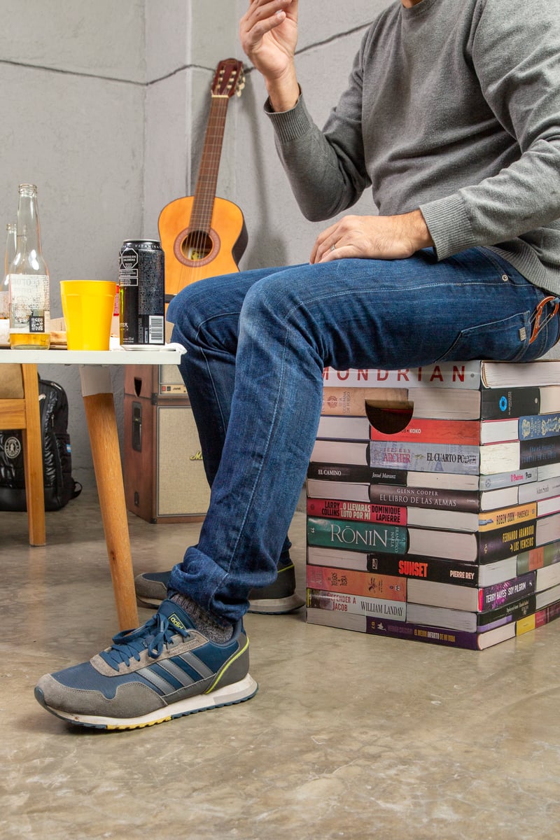 Persona sentada sobre mueble de cartón Cartón Nomade estampado con libros.