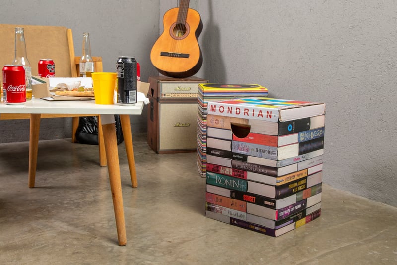Mueble de cartón Cartón Nomade con diseño de biblioteca junto a mesa y guitarra.