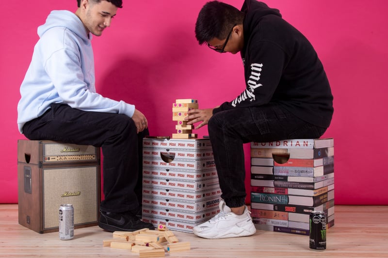 Dos personas jugando Jenga sentadas sobre muebles de cartón Cartón Nomade.