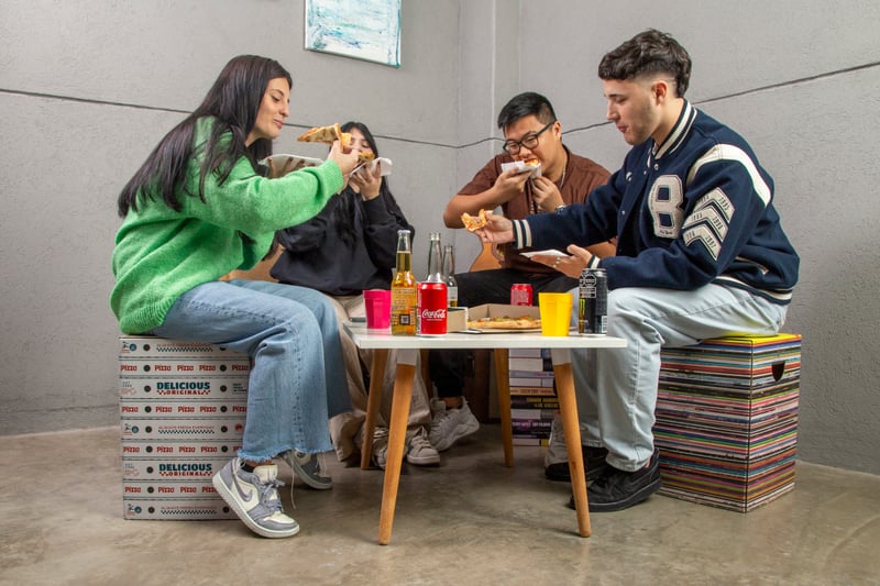 Grupo de jóvenes usando muebles de cartón Cartón Nomade durante una comida.