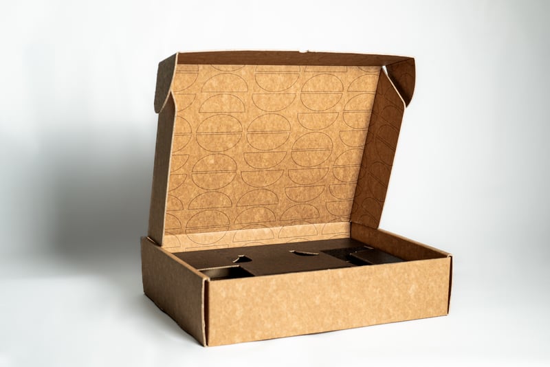 Caja mailer kraft Don abierta mostrando cuna troquelada negra con divisiones.
