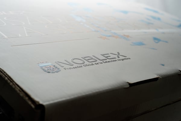 Caja Noblex celeste y blanca con identidad deportiva.